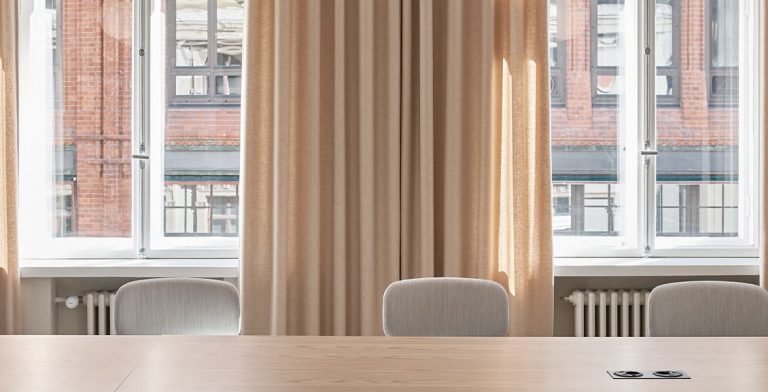 Helsinkiläisen toimiston neuvotteluhuone, jossa on ikkunoilla Fabrican paloturvalliset, beiget sivuverhot.